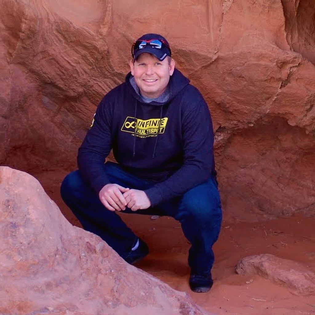 Matt, founder of Plantiful Meal, crouching inside a red-rock arch on a desert hike.